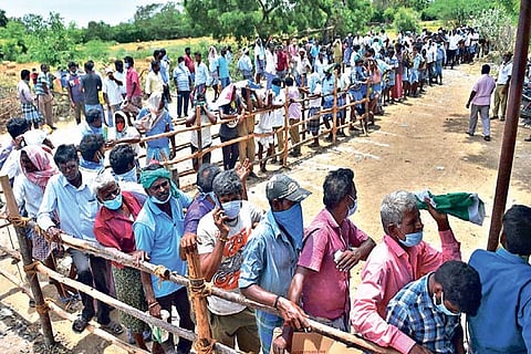 People stand in a queue to buy liquor without following social distancing norms in Chengalpattu