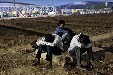 File Photo: Migrant workers rest as they wait to cross the border to reach their home state(Reuters)