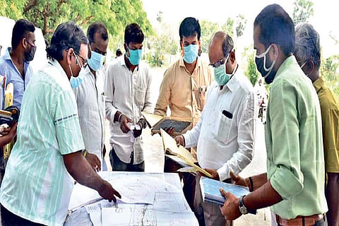 Tiruchy Collector S Sivarasu inspecting the map of the proposed road near Kallanai in Tiruchy