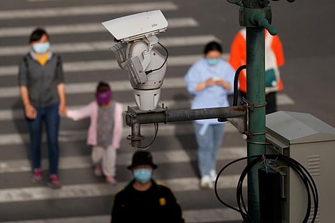 A CCTV security surveillance camera overlooks a street as people walk following the spread