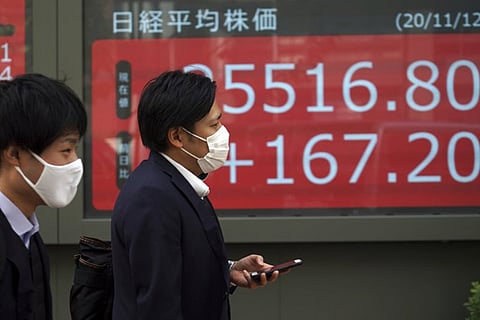 People walk past an electronic stock board showing Japan's Nikkei 225 index at a securities firm