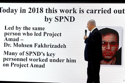 A 2018 photo shows Israeli PM Netanyahu alongside an image of Iranian nuclear scientist Fakhrizadeh