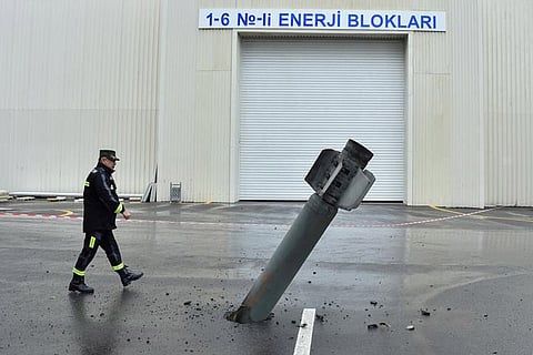 A sapper works next to an unexploded BM-30 Smerch rocket allegedly fired by Armenian forces