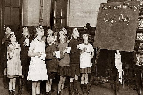 Children in England, circa 1935, gargling as a precaution against the influenza epidemic
