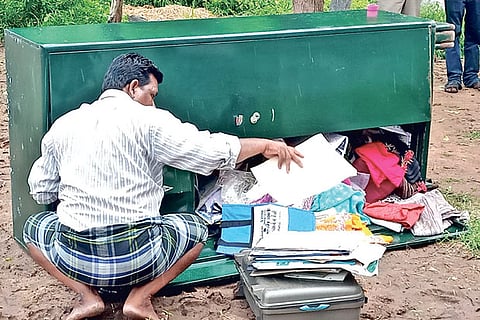 A person checks the remaining contents of the almirah lifted from a house by miscreants