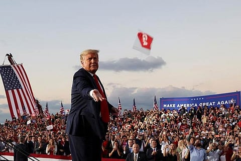 President Trump throws a face mask from the stage during a campaign rally