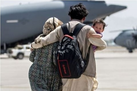 A family walks towards a US flight to leave Kabul (Credit: Reuters)