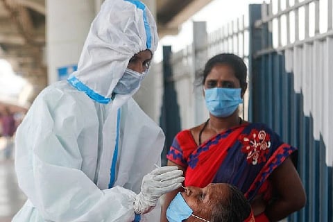A healthcare worker in PPE collects a swab sample from a woman (Credit: Reuters)