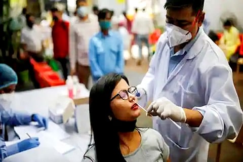 A healthcare worker collects a swab sample from a woman in New Delhi (Credit: Reuters)