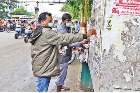 Workers ripping off posters around city