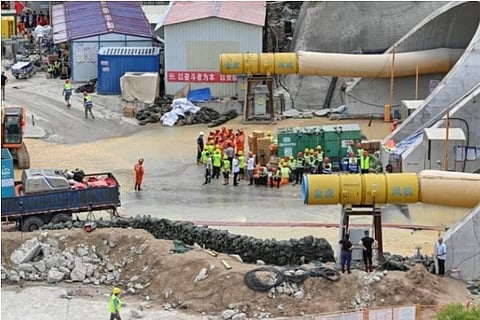 Rescue workers gather at the entrance of the flooded Shijingshan tunnel (Credit: Reuters)