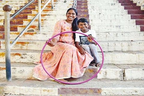Aadhav Sugumar with his mother Indu sitting on the steps of Kumaran Kundram Temple