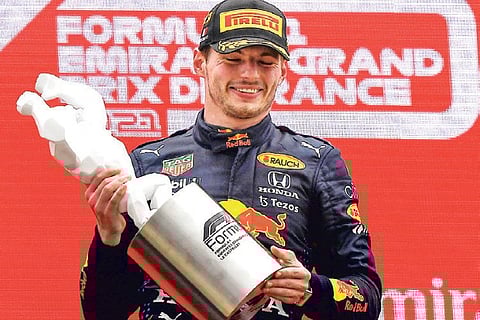 Max Verstappen celebrates on the podium with the trophy