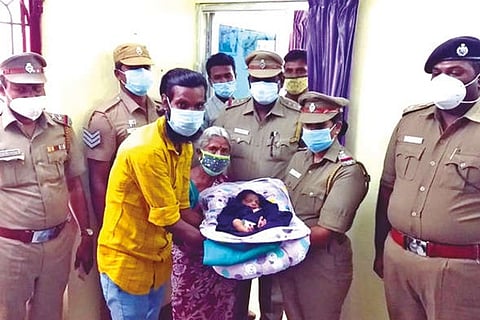 Police handing over the rescued baby to its father Arul Mani in Dharmapuri on Tuesday
