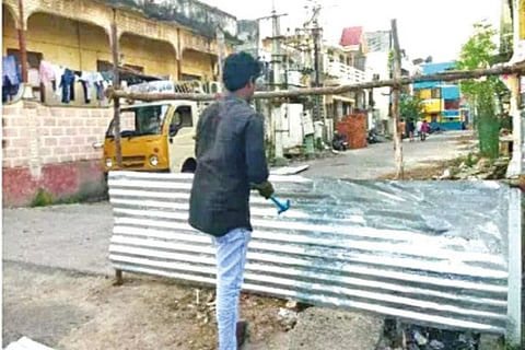A civic body worker barricading a street in Chengalpattu after 23 people tested positive for COVID