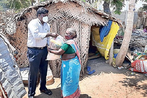 A volunteer gives a packet of essentials to a labourer