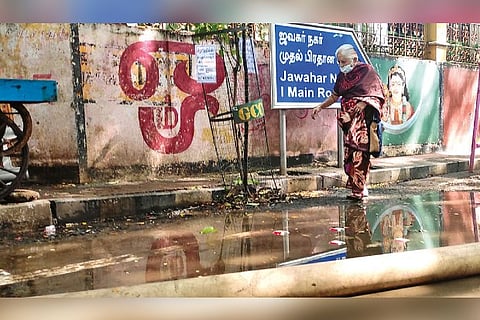 An elderly woman crossing a pool of rainwater at Jawahar Nagar