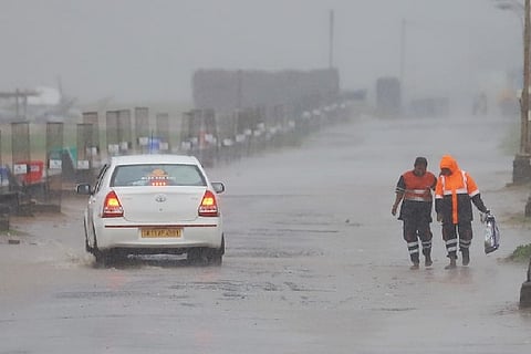 Sanitation workers trudging through the heavy rain. Photo: Justin