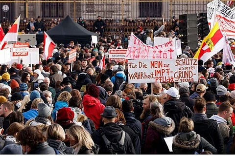 Demonstrators hold flags and placards as they gather to protest (Image Courtesy: Reuters)