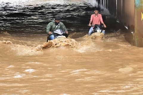 Commuters wade through a waterlogged underpass at Kodigehalli in Bengaluru (Image Courtesy: PTI))