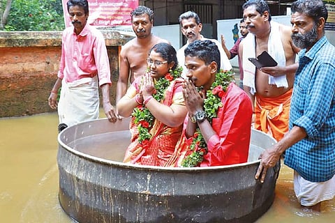 Akash and Aishwarya wade through a waterlogged area in large cooking vessel before marriage, in Alappuzha