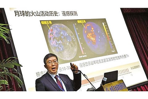 Li Xianhua speaks near a screen showing volcano activities on moon