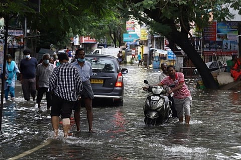 People wading through a flooded road (Image credit: Manivasagan)