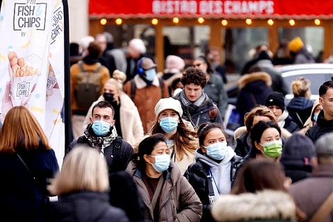 People, wearing protective face masks, walk on the Champs Elysees Avenue in Paris (Credit: Reuters)