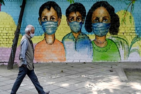 A man walks past in front of a mural depicting Covid-19 coronavirus awareness (Credit: Reuters)