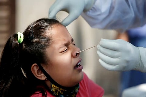 A doctor takes a nasal swab to test a girl for the coronavirus (Credit: Reuters)