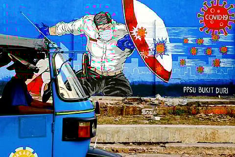 A rickshaw taxi passes a mural promoting awareness of the coronavirus (Credit: Reuters)