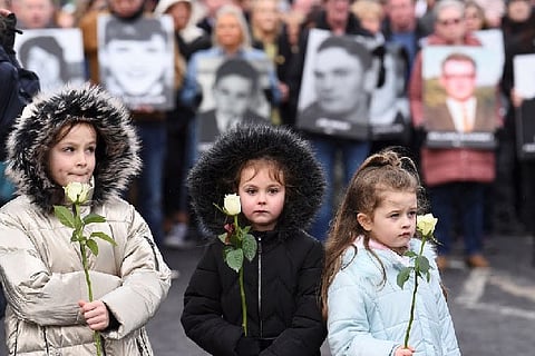 Children holding flowers in respect of those slain 50 years ago.