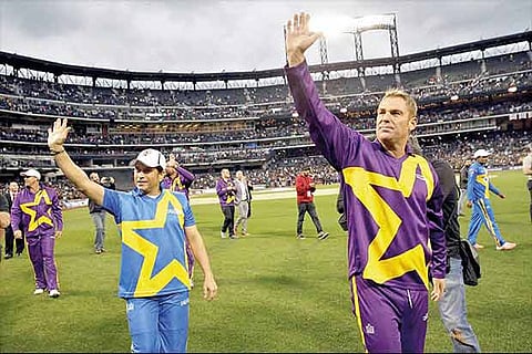 Sachin and Warne wave at fans as they take a lap around the field