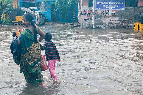 A mother and son wade through a water-logged street in adyar, Chennai