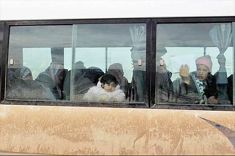 A woman displays a letter showing medical permission as she and other attempt to enter Turkey