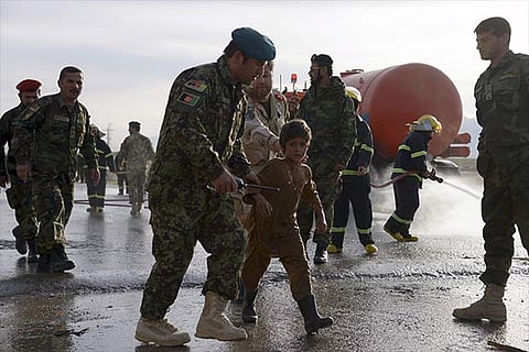 An Army officer helps an injured boy from the site of a suicide attack on the outskirts of Mazar-i-S