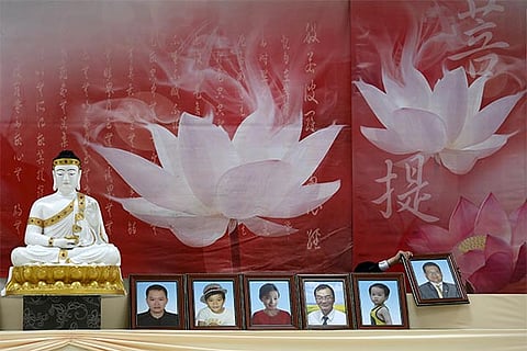 A worker places a photo of a victim at a mass funeral