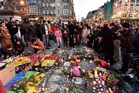 People bringing flowers and candles to mourn at Place de la Bourse in the center of Brussels