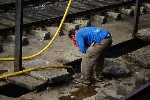 A tourist drinks water from a pipe at Rameswaram station