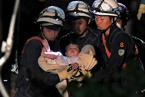 An eight-month-old baby is carried by workers who rescued from her collapsed home