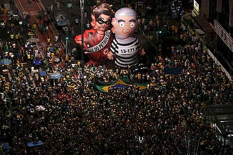 Inflatable dolls of Prez Dilma Rousseff (L) soar over crowds watching proceedings against her on TV
