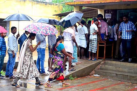 Despite rains, voters standing in a long queue outside a booth in Madurai on Monday