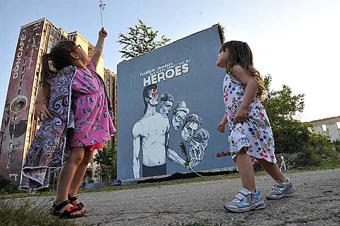Bosnian children dance in front of the mural