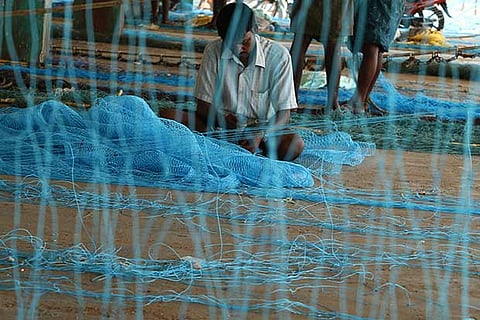 A fisherman knits a new fishing net near Kasimedu fishing harbour in Chennai (Photo: Prakaash)
