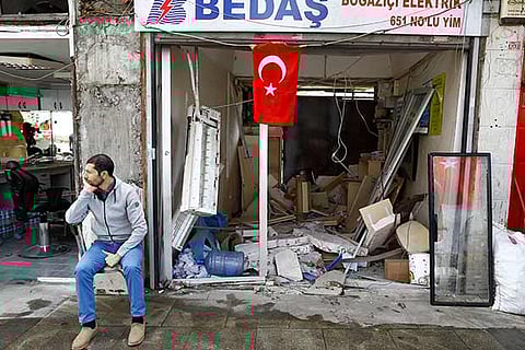 A man sits in front of a damaged shop near the scene of Tuesday?s car bomb attack