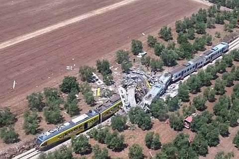 Two passenger trains are seen after a collision in the middle of an olive grove