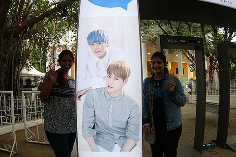 Two viewers posing with the standee of Eddy and Simba of the JJCC band