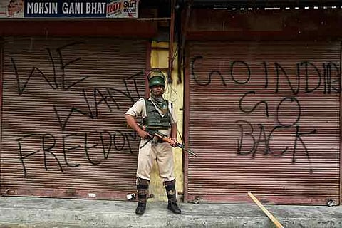 A security jawan stands guard on 49th day of curfew and strike in Srinagar on Friday