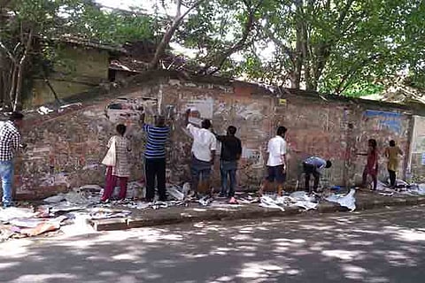 Volunteers remove posters from a wall on Barnaby Road