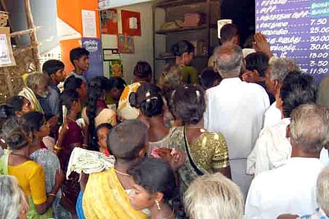 A file photo of people waiting at a ration shop to collect provisions